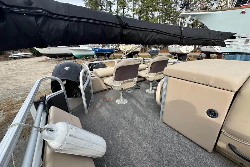 Slide: The Image of 2017 SUNTRACKER TRI-TOON boat interior with seating and motor, docked among other boats. - 32