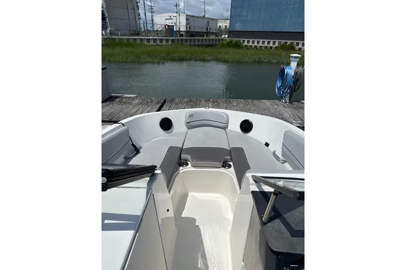 Slide: The Image of 2023 Bayliner VR6 Bowrider OB interior at dock, showcasing seating and water view. - 6