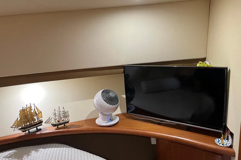 Slide: The Image of 2005 Silverton 34 Convertible interior with model ships, fan, and TV on wooden shelf. - 10