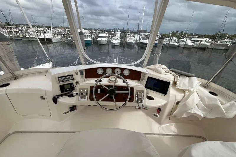 Slide: The Image of 2005 Silverton 34 Convertible yacht helm with marina view, featuring navigation instruments and steering wheel. - 45