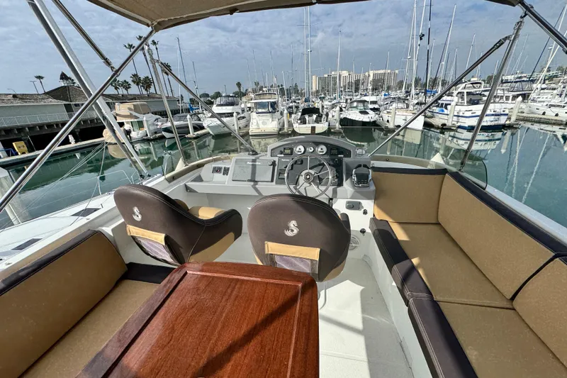 Slide: The Image of 2017 Beneteau Swift Trawler 44 interior with helm, seating, and marina view. - 21