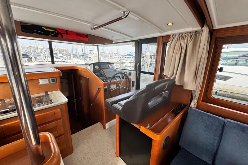 Slide: The Image of 2017 Beneteau Swift Trawler 44 interior with helm, seating, and marina view. - 43
