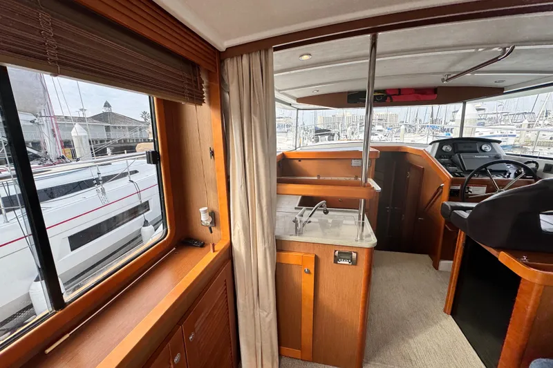 Slide: The Image of Interior of 2017 Beneteau Swift Trawler 44, featuring helm and kitchenette with marina view. - 46