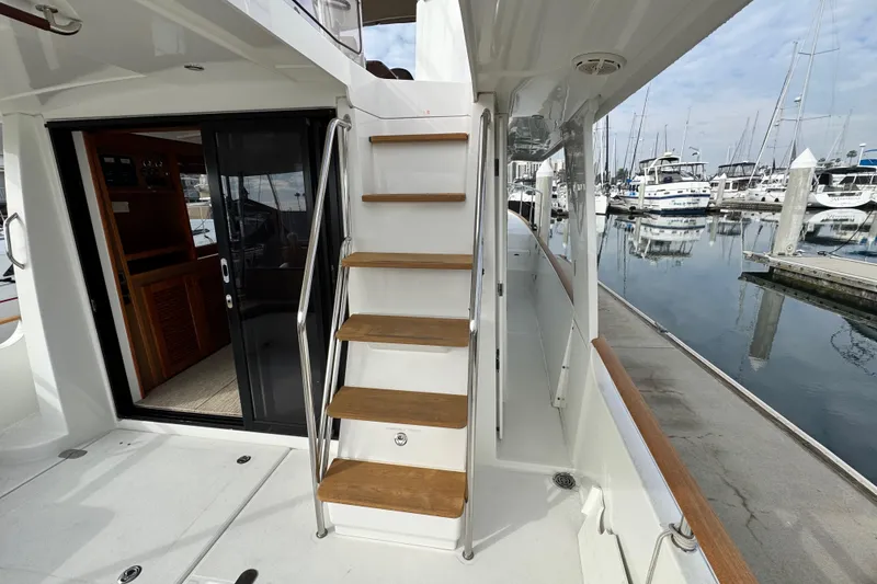 Slide: The Image of 2017 Beneteau Swift Trawler 44, featuring wooden steps and marina view. - 52