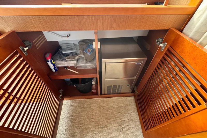 Slide: The Image of Wooden cabinet interior on 2017 Beneteau Swift Trawler 44, featuring storage and a compact fridge. - 9