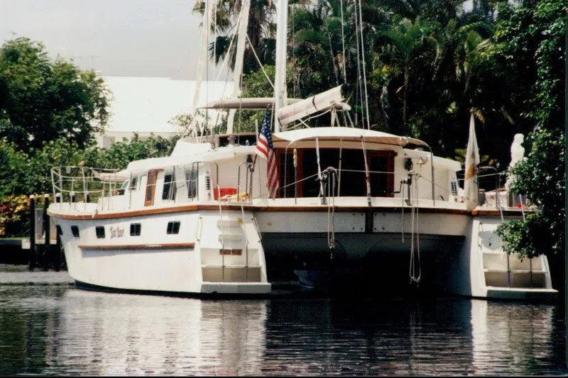 Slide: The Image of Custom 60 yacht from 1985 docked near lush greenery. - 1