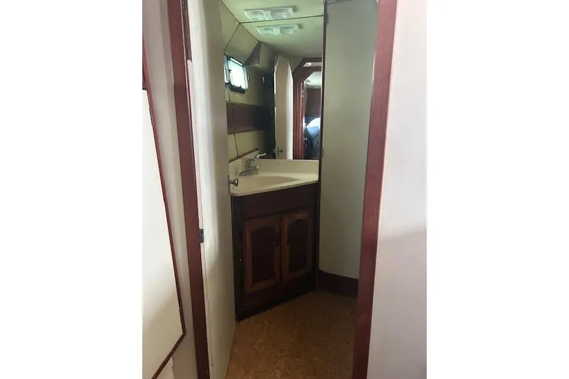 Slide: The Image of Interior of a 1985 Custom model 60, featuring a compact bathroom with a sink and mirror. - 18