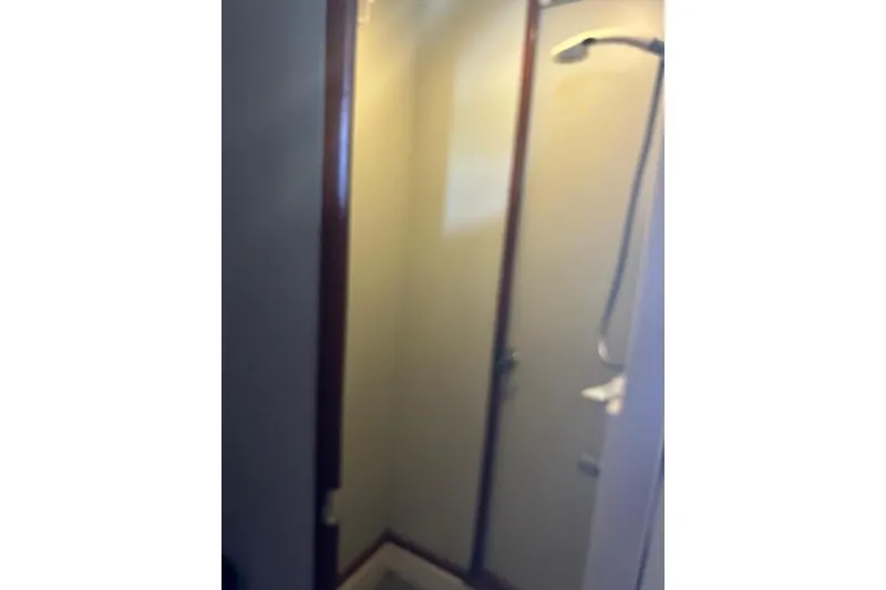 Slide: The Image of Compact shower area in a 1985 Custom 60 model, featuring a glass door and showerhead. - 57