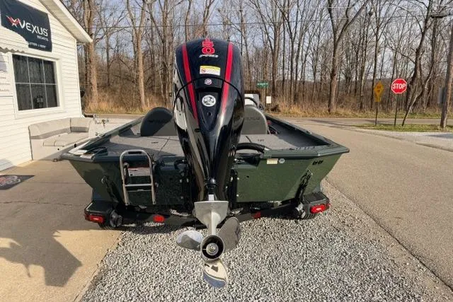 Slide: The Image of 2026 Vexus AVX1980 boat with outboard motor, parked on gravel near a wooded area. - 15