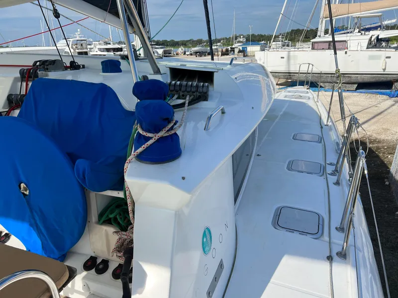 Slide: The Image of 2008 Lagoon 420 catamaran docked at a marina, featuring a clean deck and blue covers. - 16