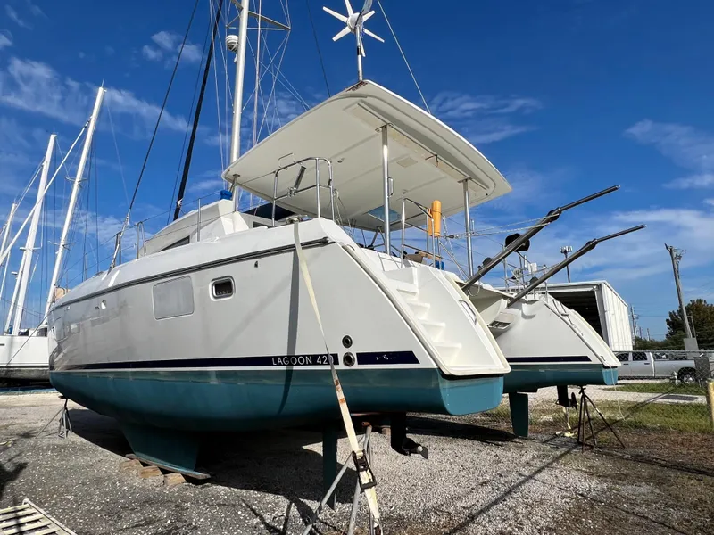 Slide: The Image of 2008 Lagoon 420 catamaran on dry dock under clear blue sky. - 8