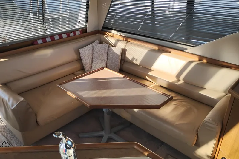 Slide: The Image of 2000 Bayliner 3988 Command Bridge Motoryacht interior with beige seating and wooden table. - 23