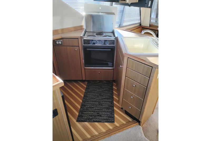 Slide: The Image of 2000 Bayliner 3988 Command Bridge Motoryacht kitchen with stove, sink, and wood cabinetry. - 30
