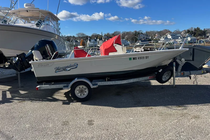 Slide: The Image of 2023 Boston Whaler 170 Montauk boat on trailer, docked at marina under clear blue sky. - 1