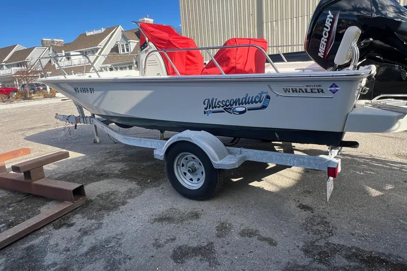 Slide: The Image of 2023 Boston Whaler 170 Montauk boat on trailer, parked outdoors with red covers. - 2
