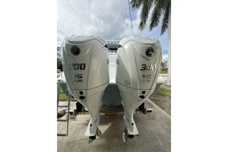 Slide: The Image of 2025 Sea Hunt Escape 28 boat on trailer, parked in residential area under cloudy sky. - 10