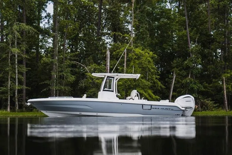 Slide: The Image of 2025 Sea Hunt Escape 28 boat interior with open storage compartment on calm water. - 2