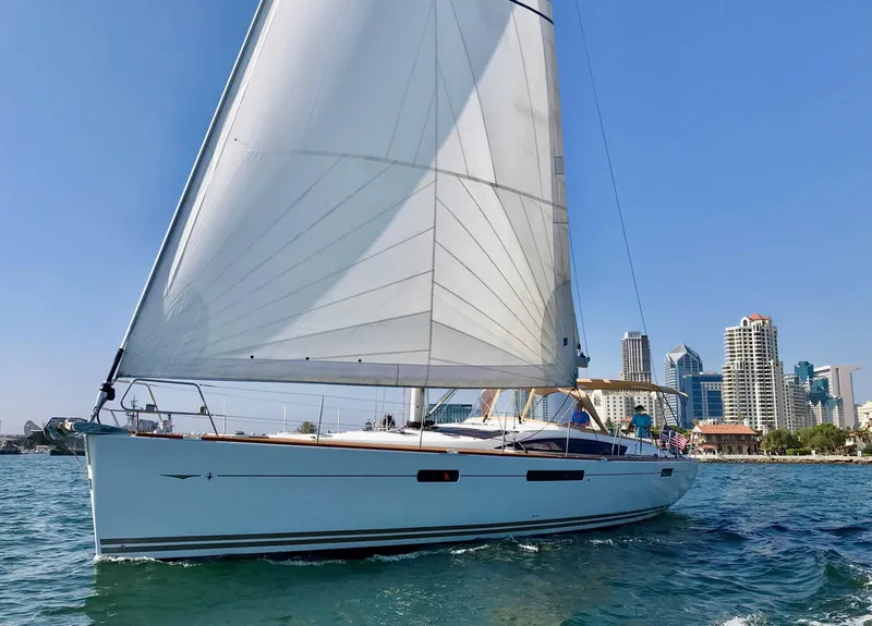 The Image of 2014 Jeanneau 57 sailboat cruising near city skyline on a sunny day. - 0