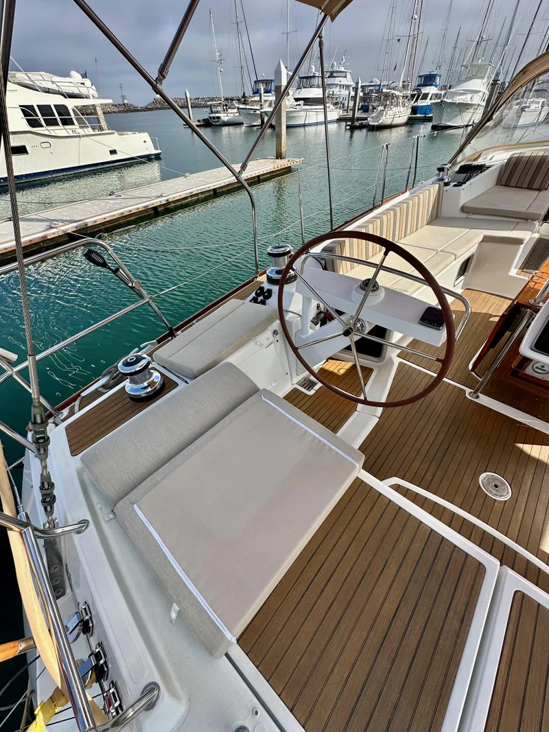 Slide: The Image of 2014 Jeanneau 57 yacht cockpit with wooden deck, steering wheel, and marina view. - 20