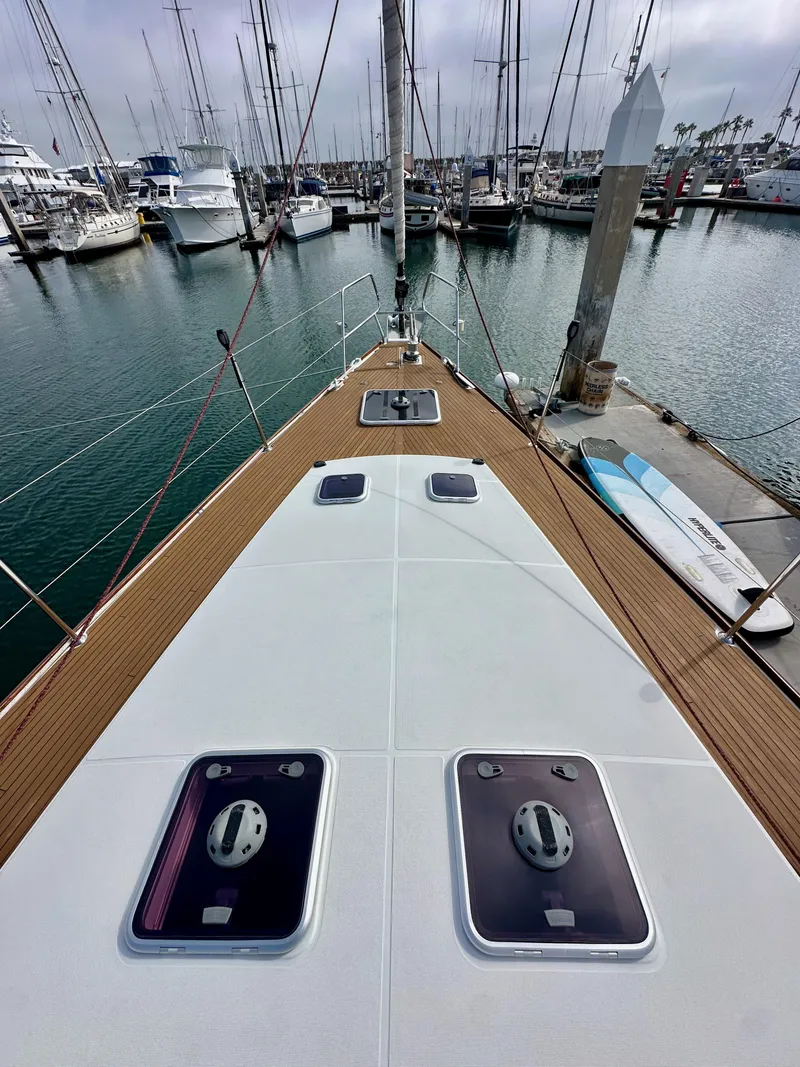 Slide: The Image of 2014 Jeanneau 57 yacht deck view in marina, showcasing sleek design and moored boats. - 42