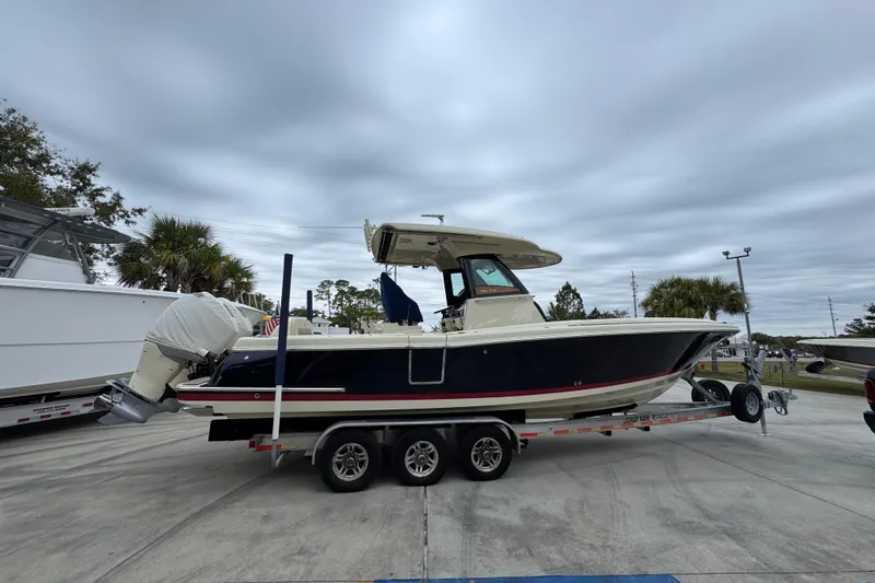 Slide: The Image of 2020 Chris-Craft Catalina 30 boat on trailer, parked outdoors under cloudy sky. - 10