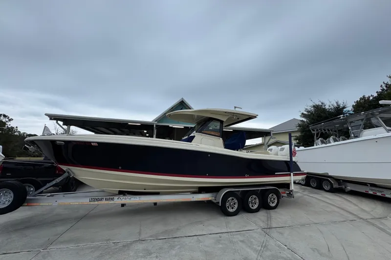 Slide: The Image of 2020 Chris-Craft Catalina 30 boat on trailer, parked outdoors under cloudy sky. - 2