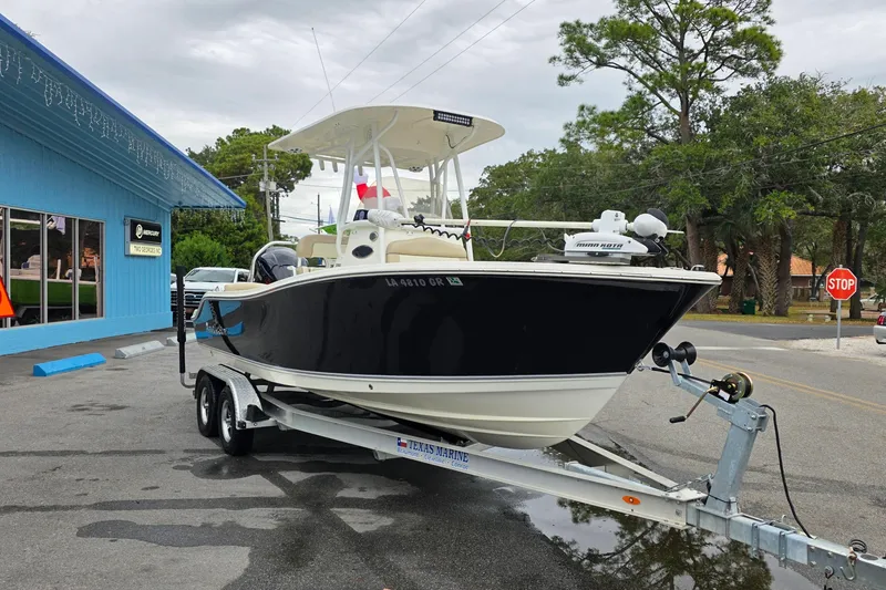 Slide: The Image of 2018 NauticStar 2302 Legacy boat on trailer outside a blue building. - 2