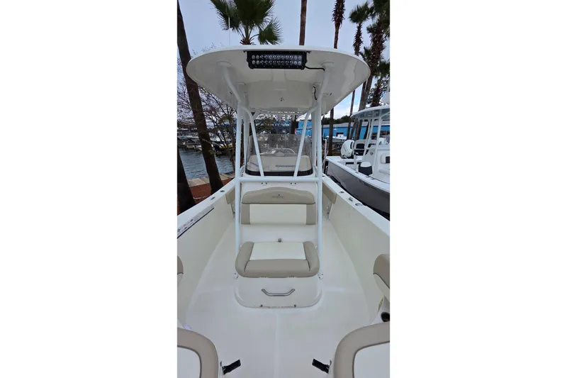 Slide: The Image of 2018 NauticStar 2302 Legacy boat interior with seating and console, docked near palm trees. - 7