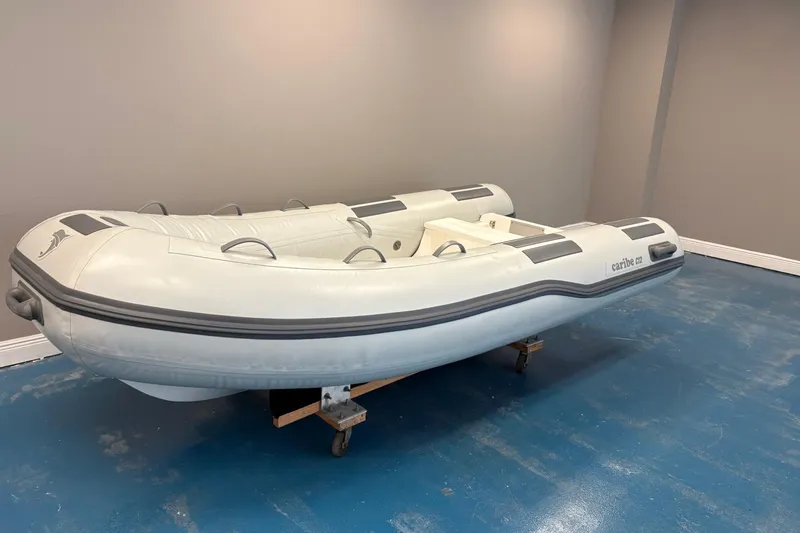 Slide: The Image of 2024 Caribe C-12 inflatable boat displayed indoors with contact information and website. - 2
