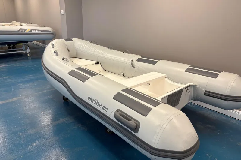 Slide: The Image of 2024 Caribe C-12 inflatable boat displayed indoors with tropical decor. - 3