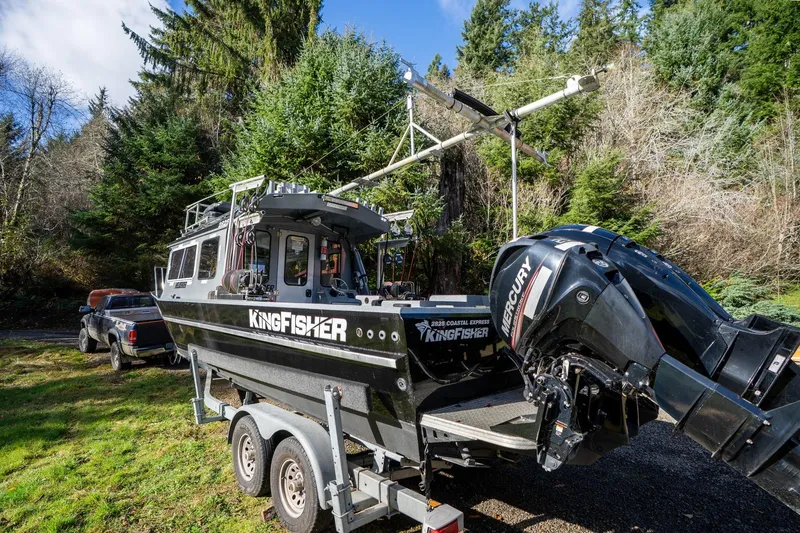 Slide: The Image of 2021 KingFisher 2825 Coastal Express boat on trailer, surrounded by lush forest. - 51