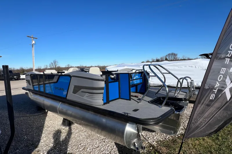 Slide: The Image of 2026 Sylvan R22 Rear Partyfish pontoon boat with blue accents, parked outdoors. - 4
