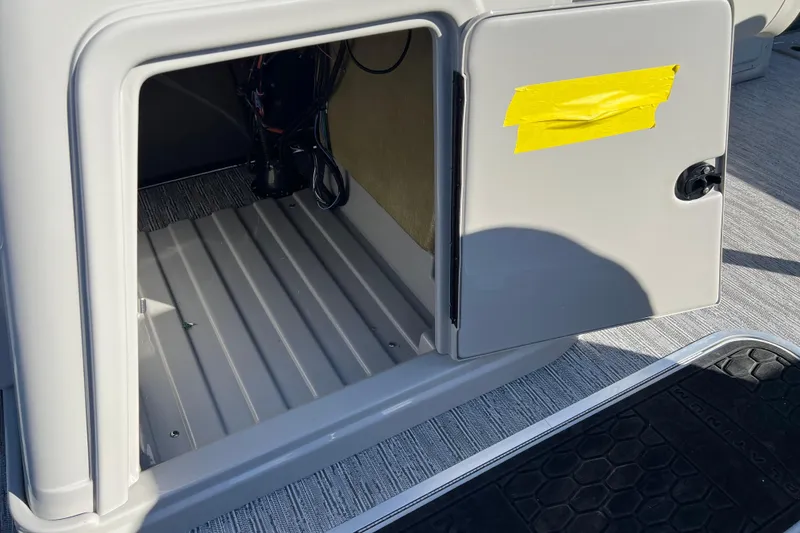 Slide: The Image of Open storage compartment on 2026 Sylvan X3 DLZ Bar boat with yellow tape on door. - 24