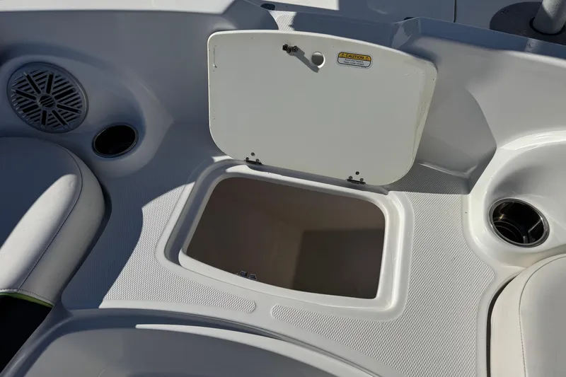 Slide: The Image of Open storage compartment on 2020 Tahoe 215 Xi boat deck, featuring speaker and cup holder. - 16