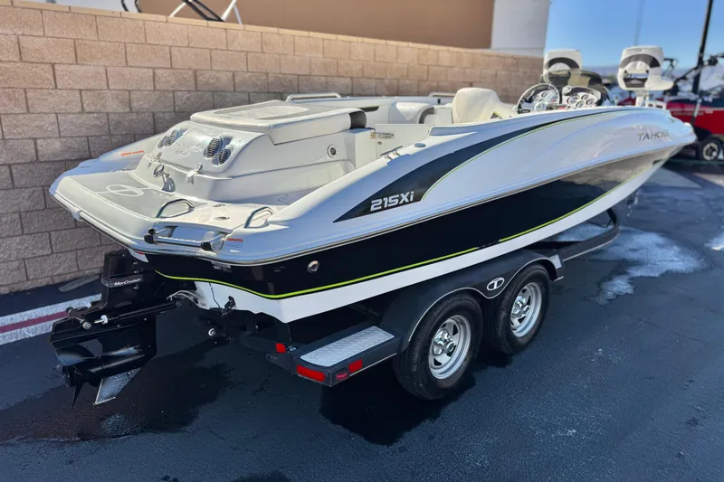 Slide: The Image of 2020 Tahoe 215 Xi boat with canopy on trailer, parked outdoors. - 5