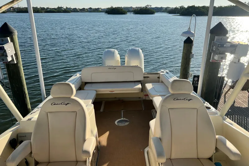 Slide: The Image of 2017 Chris-Craft Calypso 26 boat interior with seating, docked by calm waters. - 5