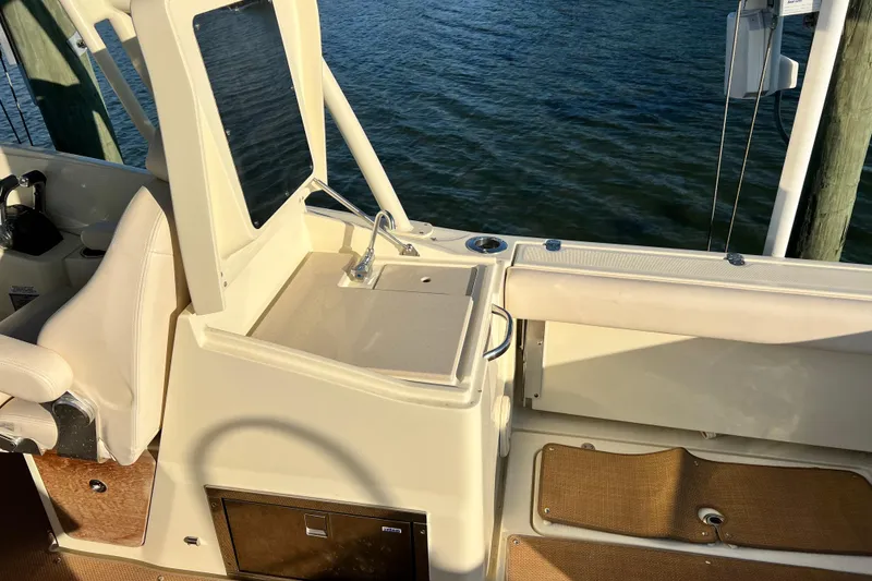 Slide: The Image of 2017 Chris-Craft Calypso 26 boat interior with sink and seating, docked by water. - 8