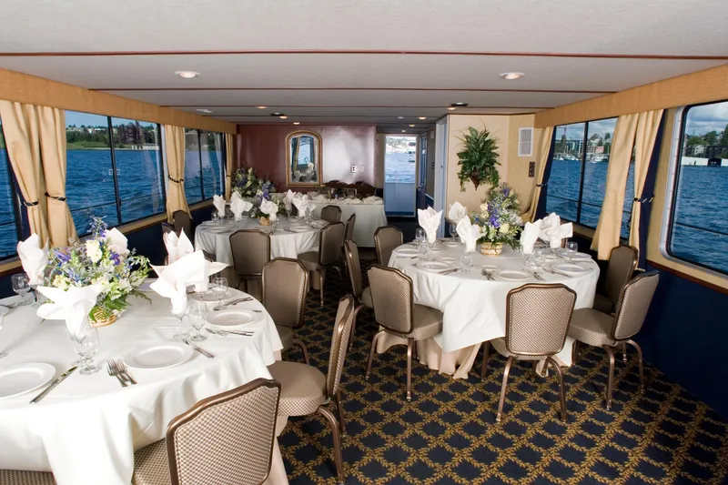 Slide: The Image of Elegant dining area on a 1993 Skipperliner 49 Passenger Yacht, featuring round tables and floral arrangements. - 3
