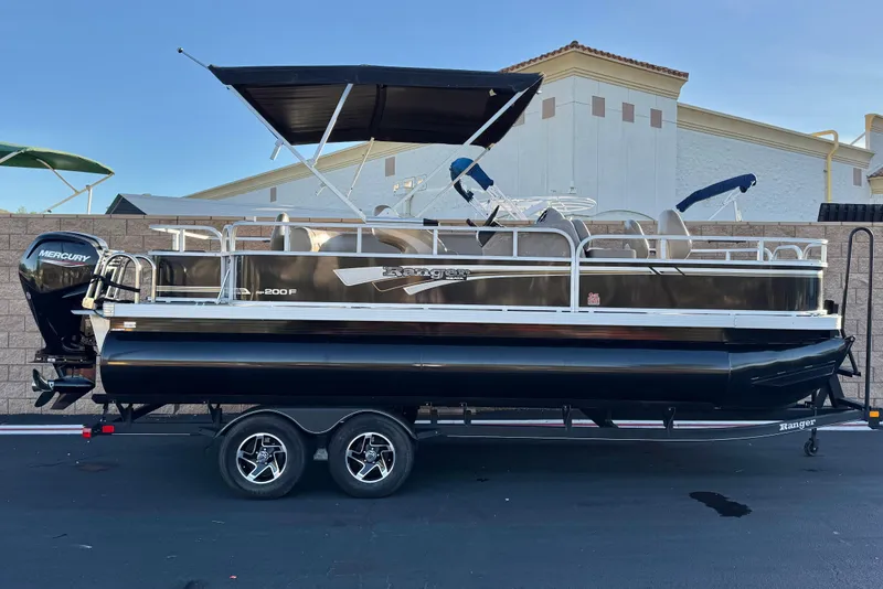 The Image of 2023 Ranger Reata 200F pontoon boat on trailer, featuring a Mercury outboard motor. - 0