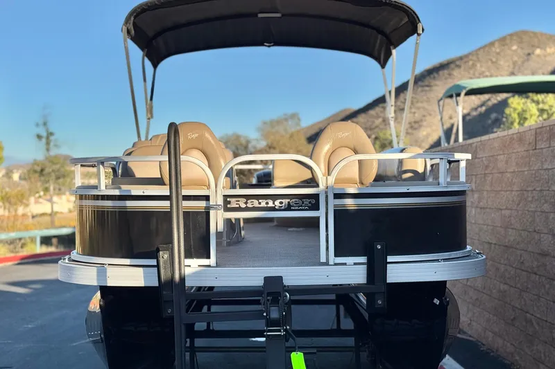 Slide: The Image of 2023 Ranger Reata 200F pontoon boat with tan seats and black exterior. - 2