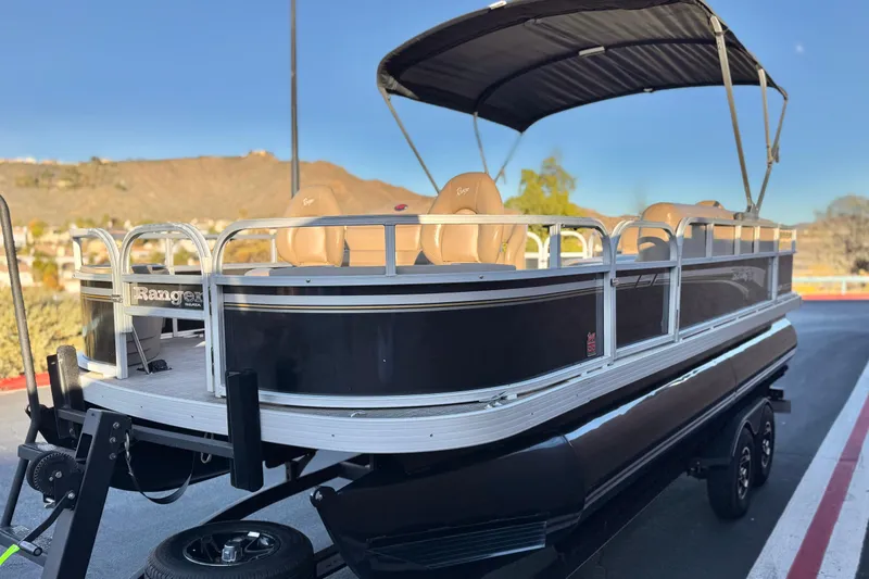 Slide: The Image of 2023 Ranger Reata 200F pontoon boat with canopy, parked on a trailer. - 3