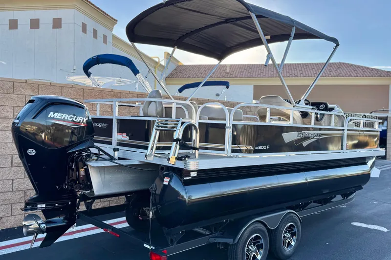 Slide: The Image of 2023 Ranger Reata 200F pontoon boat with Mercury outboard engine, parked outdoors. - 6