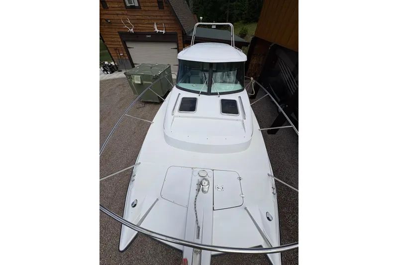 Slide: The Image of 2001 Glacier Bay 2690 Coastal Runner boat, white exterior, docked near wooden building. - 37