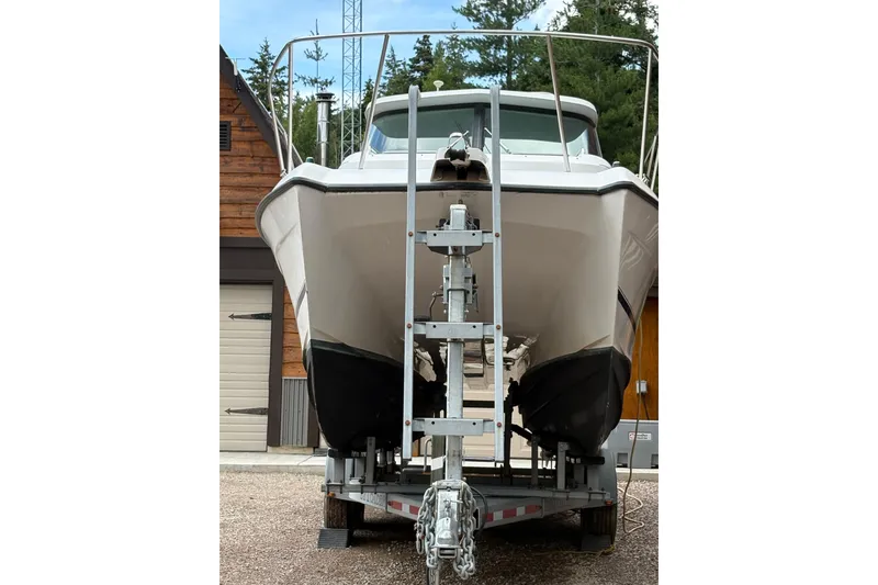 Slide: The Image of 2001 Glacier Bay 2690 Coastal Runner boat on trailer, front view, near wooden building. - 39