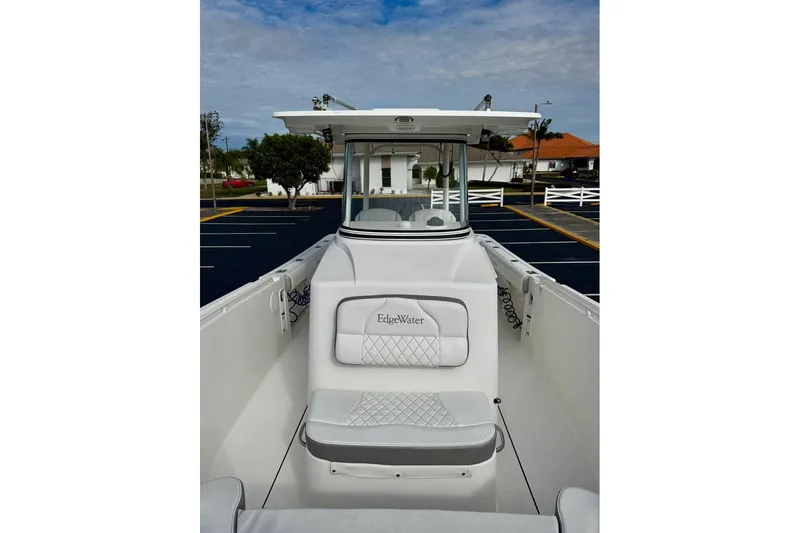 Slide: The Image of 2014 Edgewater 280CC boat with white seating and console, parked in a lot. - 13