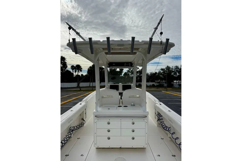 Slide: The Image of 2014 Edgewater 280CC boat interior with center console and rod holders under cloudy sky. - 32