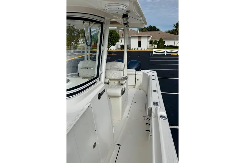 Slide: The Image of 2014 Edgewater 280CC boat interior with seating and console, parked in a lot. - 39