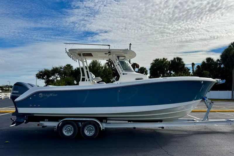 Slide: The Image of 2014 Edgewater 280CC boat on trailer, blue hull, parked outdoors under cloudy sky. - 4