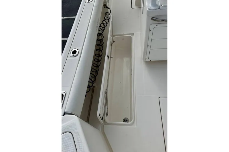 Slide: The Image of 2014 Edgewater 280CC boat interior with open storage compartment and coiled hose. - 42
