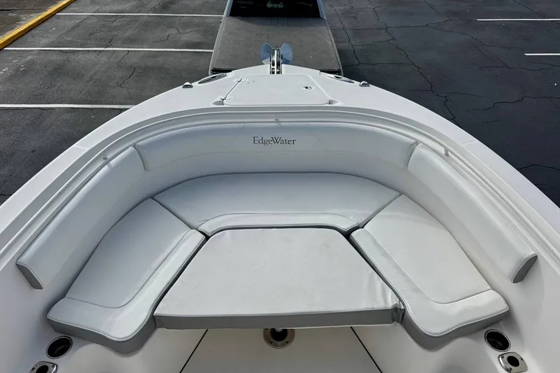 Slide: The Image of 2014 Edgewater 280CC boat with white cushioned seating in a parking lot. - 8